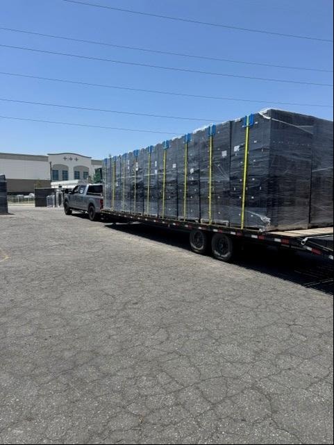 Truck pulling flatbed loaded with wrapped pallets