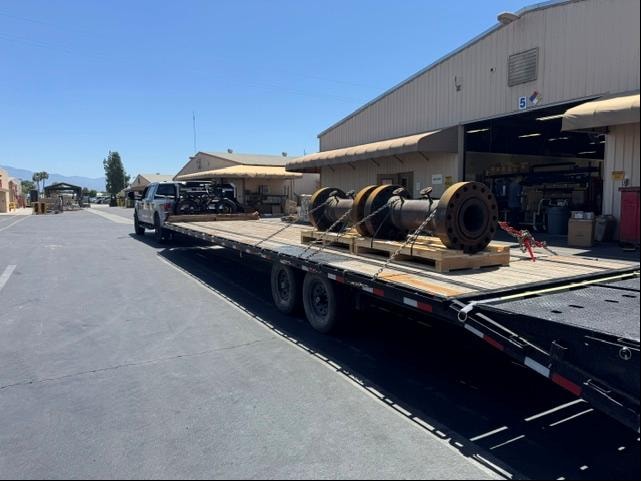 Truck with heavy equipment on flatbed at facility
